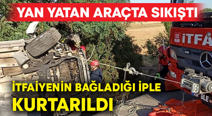 Yan yatan araçta sıkıştı, itfaiyenin bağladığı iple kurtarıldı